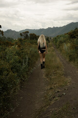 Stylish girl walks along the path against the backdrop of the mountains