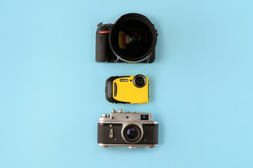 Fototapeta premium Camera evolution.Cameras of different types and generations on a blue background, top view,flat lay.