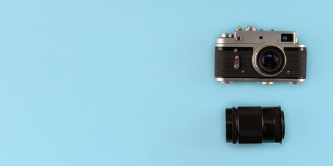 Retro photo camera with lens on blue background, top view