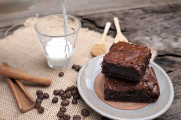 Chocolate brownies cake, and milk on a wooden table.
