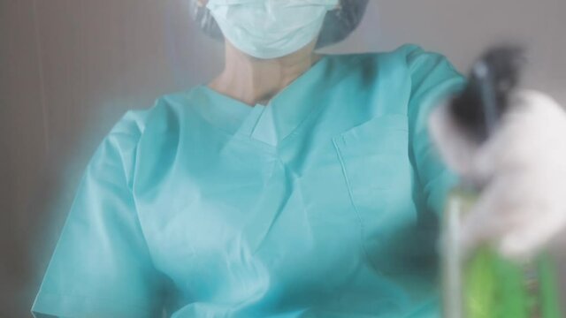 Doctor putting gloves on her arms and wearing medical mask then spray alcohol for cleaning around the Working area.