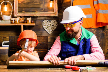 Father and son hammers nails with a hammer in a wooden board. Happy fatherhood.