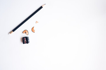 The cropped shot view of sharpened pencils of various lengths with a sharpener and pencil shavings on white background, blank copy space screen for your text message or information content.