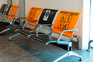 Empty seats, priority seats in the airport gate waiting area. Social distance, stickers asking not...