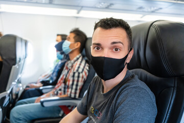 Airplane passengers are wearing medical masks on their faces. Air travel during the coronavirus pandemic. Airlines requirements.