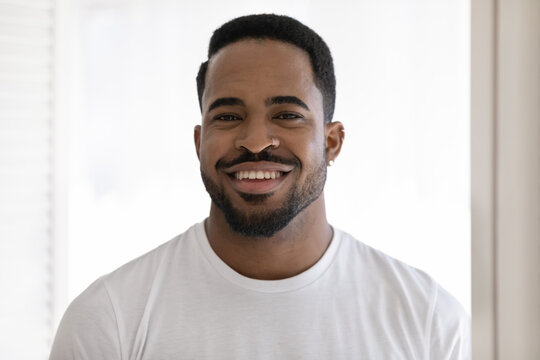 Head shot portrait smiling cheerful African American man wearing white t-shirt looking at camera, handsome young male with healthy toothy smile and smooth perfect skin posing for photo