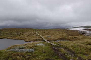 Empty hiking trail in Swede with some dark clouds, water and some snow