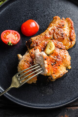 Dish of grilled pork chop with tomatoes top view with knife and slice on fork over old rustic dark wood table table close up top view