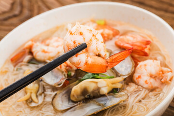 A bowl of rice noodles with shrimp and razor clams