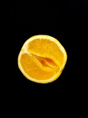 A vagina symbol. The concept of sex. Bright juicy orange on a black background.