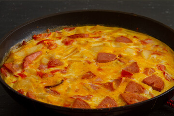 
Fritata.Rustic omelet with potatoes, tomatoes, cheese and sausage in a pan.