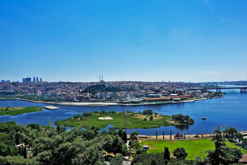 Panorama of Istanbul, summer sunny day. Bright blue Golden Horn Bay, green islands. In the distance there are many residential buildings, skyscrapers, mosques. Clear blue sky. Turkey.