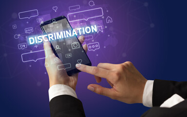 Female hand typing on smartphone with DISCRIMINATION inscription, social media concept