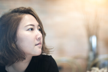 Fototapeta premium portrait of a young beautiful Asian woman with sunlight in cafe.