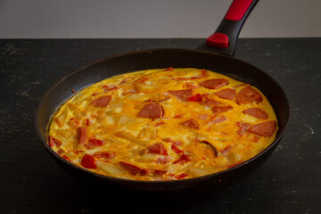 Fritata. Rustic omelet with potatoes, tomatoes, cheese and sausage in a pan.