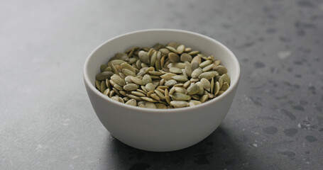 pumpkin seeds in white bowl on terrazzo countertop with copy space