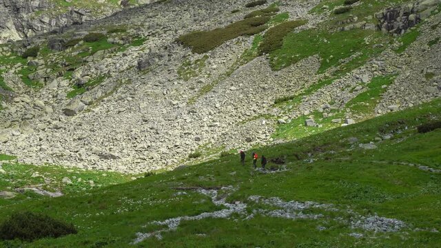 View of Velicka dolina (Velicka valley) in High Tatras mountains, Slovakia. Three hikers walking on a rocky hiking trail in clean nature and environment.