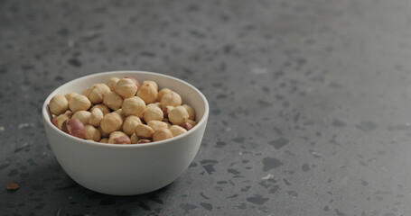 roasted hazelnuts in white bowl on terrazzo countertop