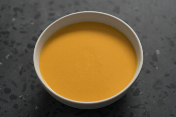Pumpkin soup in white bowl on concrete background