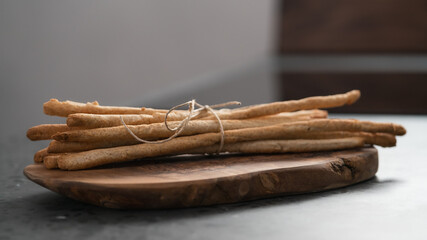 bunch of handmade wholegrain grissini tied with rope on olive board