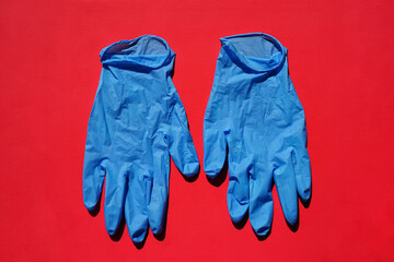 Pair of medical blue latex protective gloves on red background. Protective disposable gloves against the spread of virus, flu, coronavirus (COVID-19), bacterial. Health care and surgical concept.