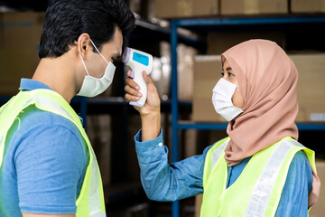 Islam Muslim asian warehouse worker take temperature to another worker