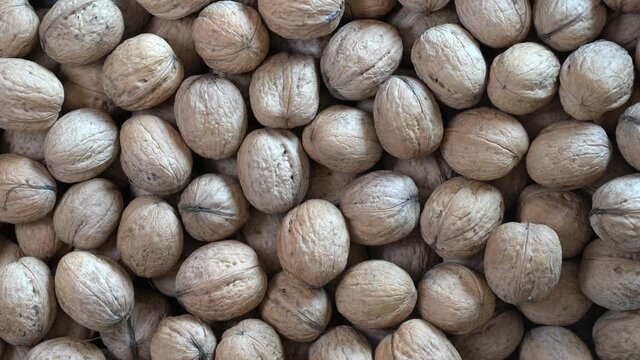 Walnuts in shell close up, top view. Abstract walnuts heap pattern background, rotates. Natural walnut background pattern texture