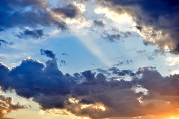 Obraz premium Evening sunset sky with yellow blue clouds and sun rays
