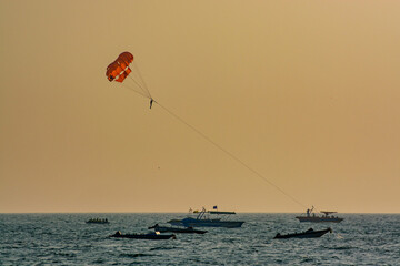 parasailing over the blue sea at sunset