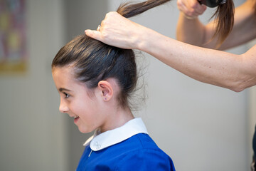 Fototapeta premium Young girl with her mother combing hair, ready for back to school day