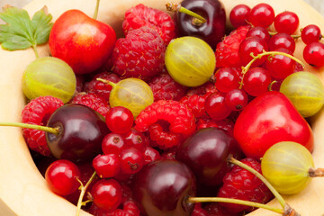 A bowl of seasonal summer fruit from a home orchard; currant, cherry, gooseberry and raspberries.