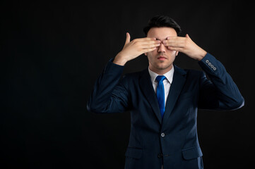 Portrait of business man wearing blue business suit and tie covering eyes like blind gesture