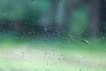 Raindrops on the surface of window panes with a green background . Natural pattern of raindrops for the background. 