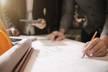 Businessman working as a team discussing data working and tablet, laptop with on on architectural project at construction site at desk in office.