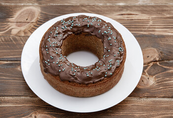 Sweet, fresh, isolated birthday bagel with chocolate on white plate, wooden background.