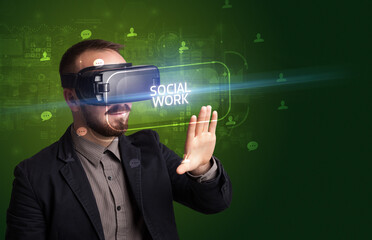 Businessman looking through Virtual Reality glasses with SOCIAL WORK inscription, social networking concept