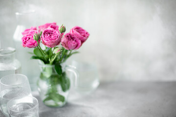 bouquet of purple garden roses in a glass jug