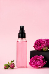 Obraz na płótnie Canvas pink skin tonic in a plastic bottle with rose flowers