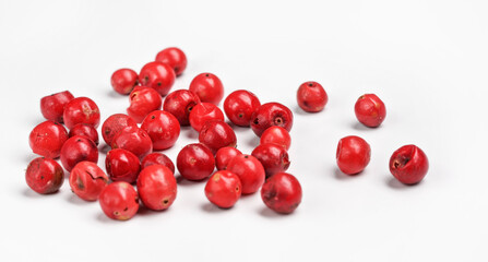 Red or Pink peppercorn scattered on board, closeup photo isolated with white background