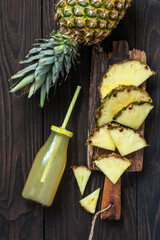 Bottle of pineapple juice with fresh fruit, flat lay