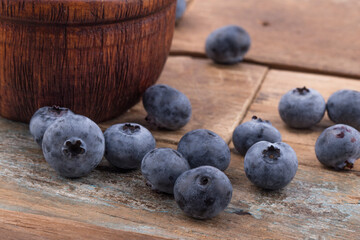 Ripe blueberries in a bowl on a wooden table.