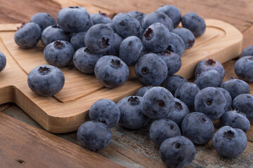 Ripe blueberries in a bowl on a wooden table.
