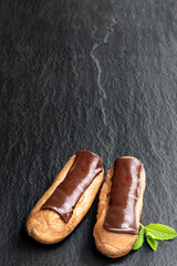 Chocolate eclairs on black stone background