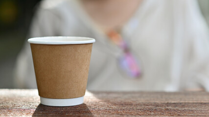 Close-up shot of Take away coffee mug placed on a wooden table.