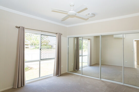 Bedroom in new house with ceiling fan, sliding glass mirrors doors and sliding glass windows