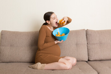 Pregnant woman is eating potato chips because of salt cravings. Unhealthy junk food during pregnancy concept