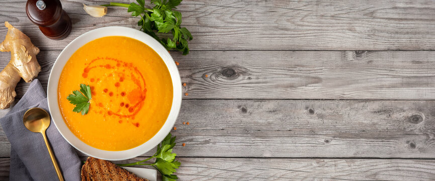 Top view of winter spicy lentil soup on graw wooden background