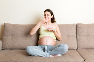 Pregnant woman enjoys eating different donuts resting on the sofa. Unhealthy desserts during pregnancy concept