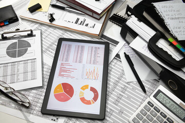 business office desk closeup - tablet computer with tables and graphs on the screen, financial...