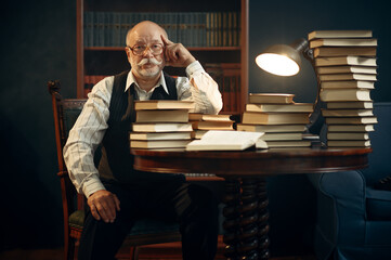 Elderly writer sitting at the table with books